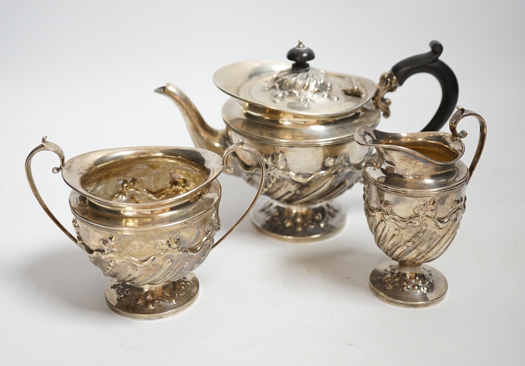 A late Victorian repousse silver three piece bachelor's tea set, double stamped maker's marks, London, 1890, gross weight 21.8oz.